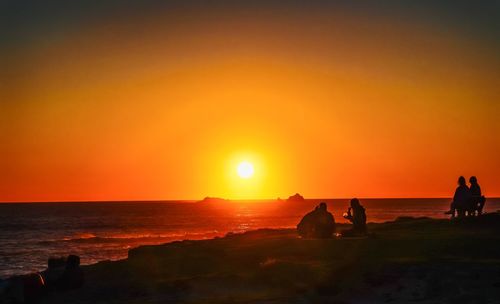 Silhouette of people on beach against sky during sunset