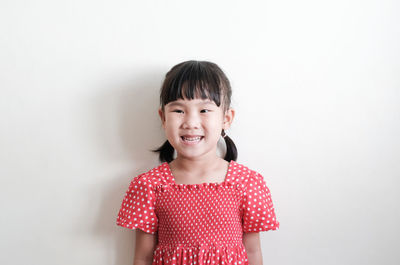 Portrait of smiling girl standing against white background