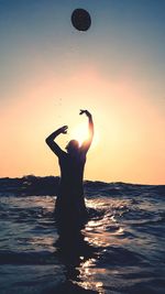 Silhouette of man in sea at sunset