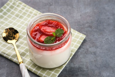 Sweet vanilla silky pudding dessert with strawberry sauce, sliced fresh strawberries and mint