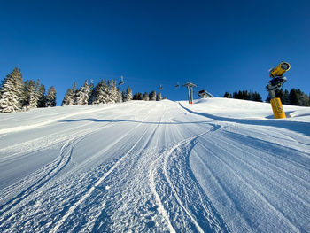 Snow covered land against clear blue sky