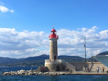 Lighthouse by sea against sky