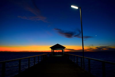 Pier over sea against sky during sunset