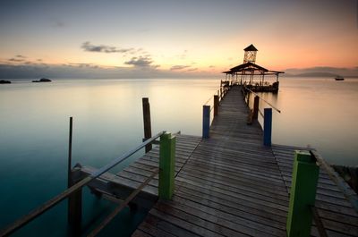 Pier over sea against sky during sunset