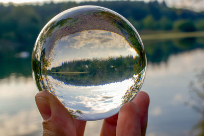 Close-up of hand holding glass with reflection of crystal ball