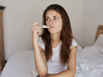 Portrait of beautiful woman sitting on bed at home