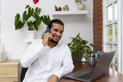 Young man using phone while sitting on table