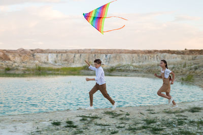 Teenagers run with a kite, outdoor activity day off.