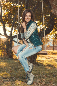 Portrait of young woman sitting on swing