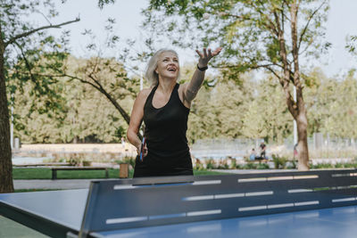 Mature woman tossing ball playing table tennis park