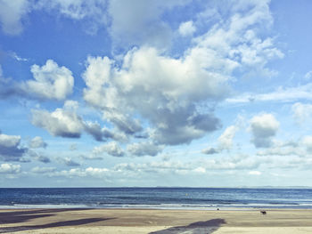 View of calm beach against cloudy sky