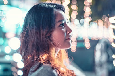 Close-up of young woman amidst illuminated lights