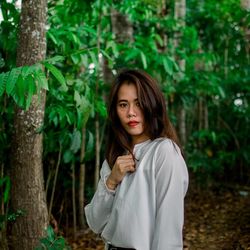 Portrait of woman standing against plants in forest