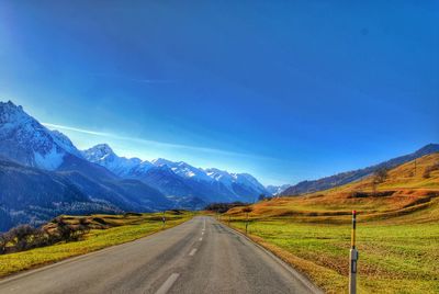 Country road and mountains against blue sky