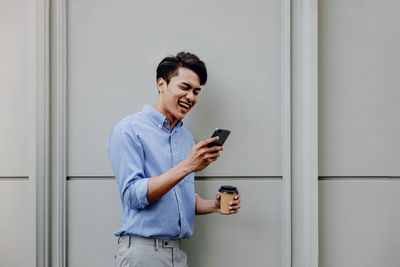 Smiling young man using mobile phone