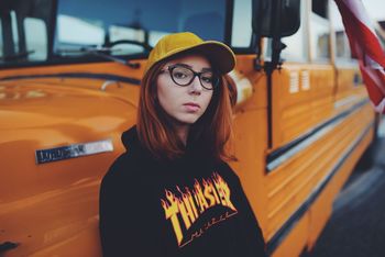 CLOSE-UP PORTRAIT OF YOUNG WOMAN STANDING BY BUS