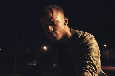 Young man against illuminated sky at night