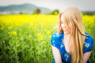 Smiling beautiful woman looking down against oilseed rape field