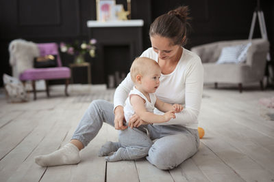 Baby boy is crying, mom comforts and pities his son on the floor in a real stylish interior.