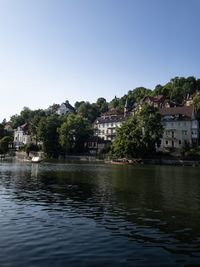 Scenic view of river by buildings against sky