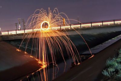 Wire wool on bridge over canal against sky at night