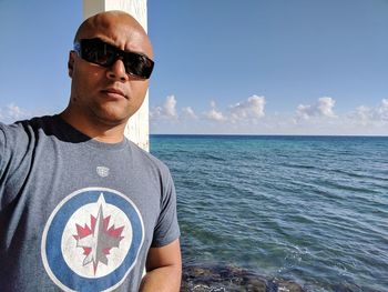 Man wearing sunglasses at sea against sky