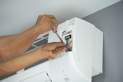 Cropped man repairing air conditioner at home