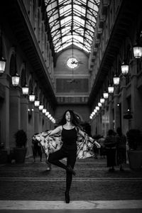 Portrait of young woman dancing in illuminated corridor of church