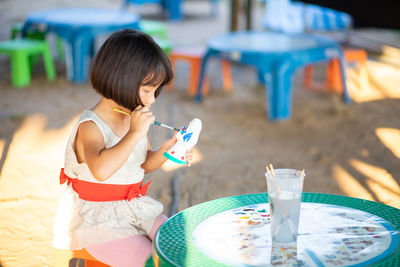 Rear view of girl sitting on table