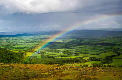 Scenic view of rainbow over agricultural field against sky