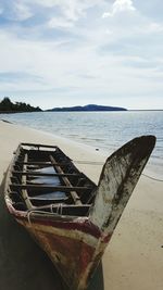 Fishing boat on beach against sky