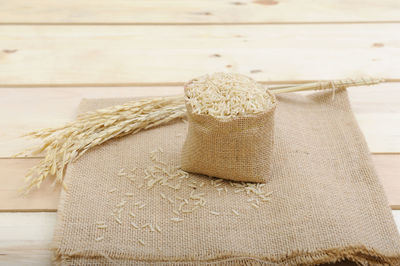 High angle view of rice in sack by wheat on table