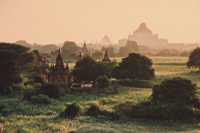 Panoramic view of temples on field against sky during sunset