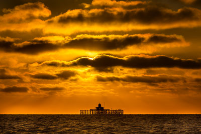 Silhouette boat in sea against orange sky