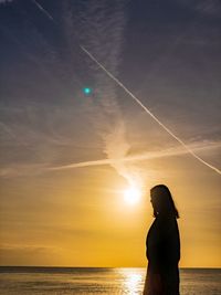 Man standing at beach against sky during sunset