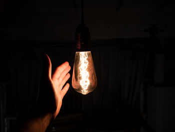 Close-up of hand holding illuminated light bulb