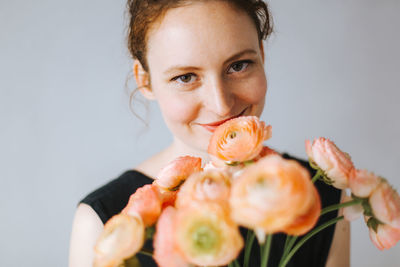 Portrait of smiling woman with flowers against wall