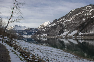 Scenic view of lake by snowcapped mountains against sky