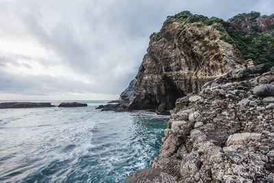 Rock formation on beach against sky