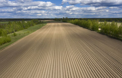 Road amidst field against sky