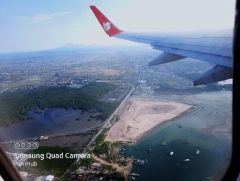 Aerial view of airplane flying over landscape against sky