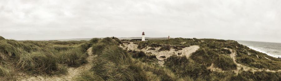 Lighthouse by sea against sky