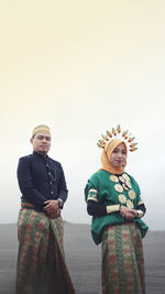 Young couple standing against clear sky