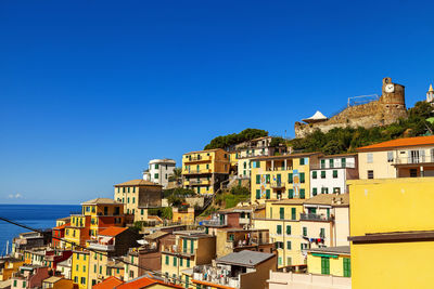 Buildings in city against clear blue sky