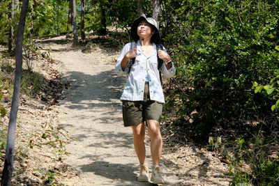 Portrait of young woman standing against plants