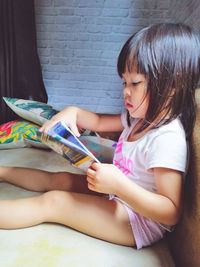 Side view of girl holding hands sitting