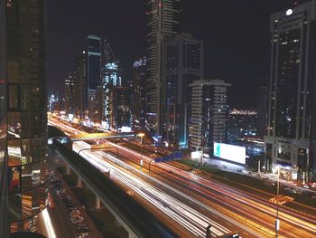 Light trails on city street by buildings at night