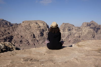 Rear view of woman sitting on rock