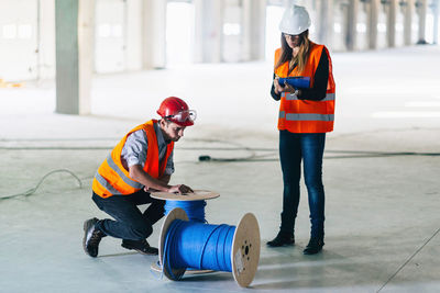 Architect with cables kneeling by coworker in parking lot