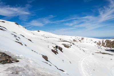 Scenic view of snow covered mountains against blue sky